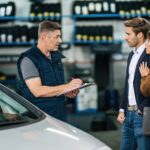Car mechanic communicating with customers at auto repair shop.